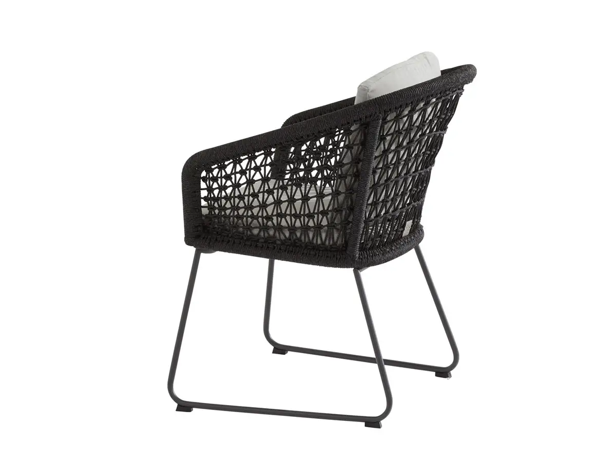 Mila Dining Stuhl: schwarzer geflochtener Outdoor-Stuhl mit Metallbeinen, abgewinkelter Rückenlehne und hellgrauen Kissen.
