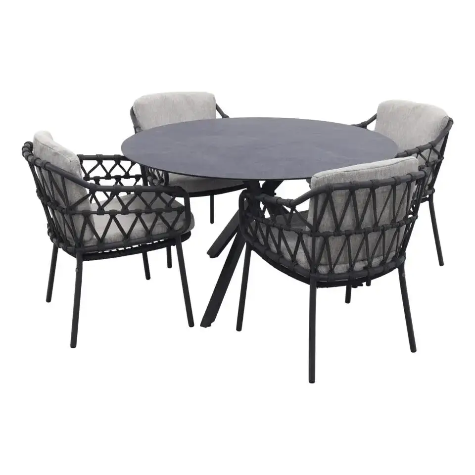 Der Locarno Dining Tisch ist ein runder, schwarzer Tisch mit vier schwarzen, geflochtenen Stühlen und hellgrauen Polstern.