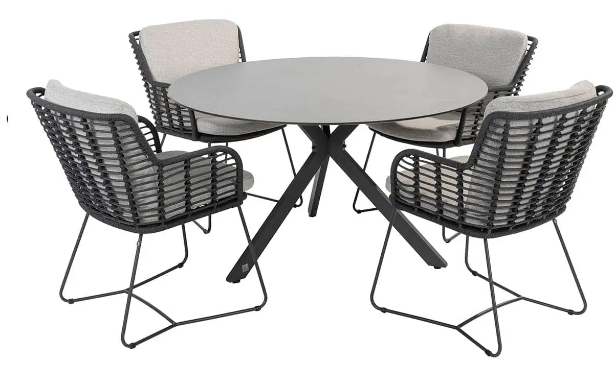 Der Locarno Dining Tisch ist ein runder grauer Tisch mit vier schwarzen geflochtenen Stühlen und hellgrauen Polstern.