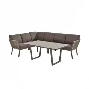Cocoon Cozy Dining Sitzgruppe: Braunes gepolstertes L-förmiges Outdoor-Sofa mit rechteckigem Tisch mit grauer Platte und Metallbeinen.