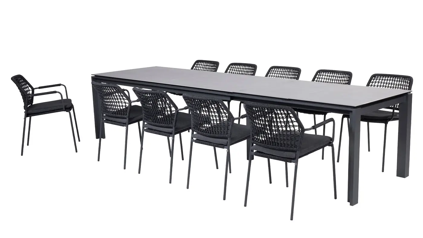 Ein Goa Dining Tisch mit acht schwarzen Stühlen rundherum und einem passenden Stuhl, der links daneben steht.