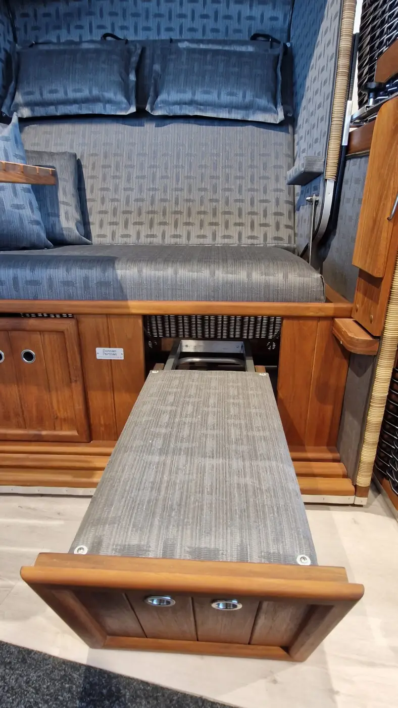 Der Strandkorb Präsident Teak verfügt über ein ausziehbares Bett unter einer gepolsterten Sitzfläche mit grau gemusterten Polstern. Gartenmöbel und Grills kaufen in Rostock, Mecklenburg-Vorpommern.