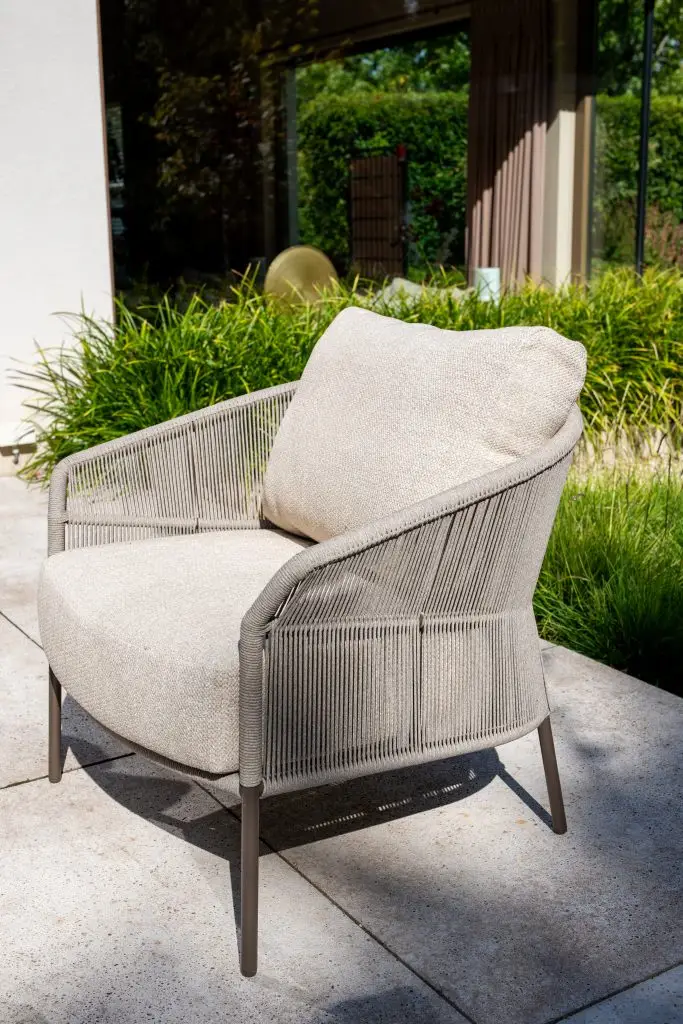 Ein Florence Sessel mit Fußhocker und Seilseiten steht auf der sonnigen Terrasse bei Glastüren und grünen Pflanzen. Gartenmöbel und Grills kaufen in Rostock, Mecklenburg-Vorpommern.