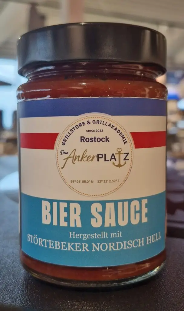 Ein Glas Bier Sauce mit blau-weiß-rotem Etikett steht neben der Honig Whisky Sauce (Kopie) auf der Ladentheke. Gartenmöbel und Grills kaufen in Rostock, Mecklenburg-Vorpommern.