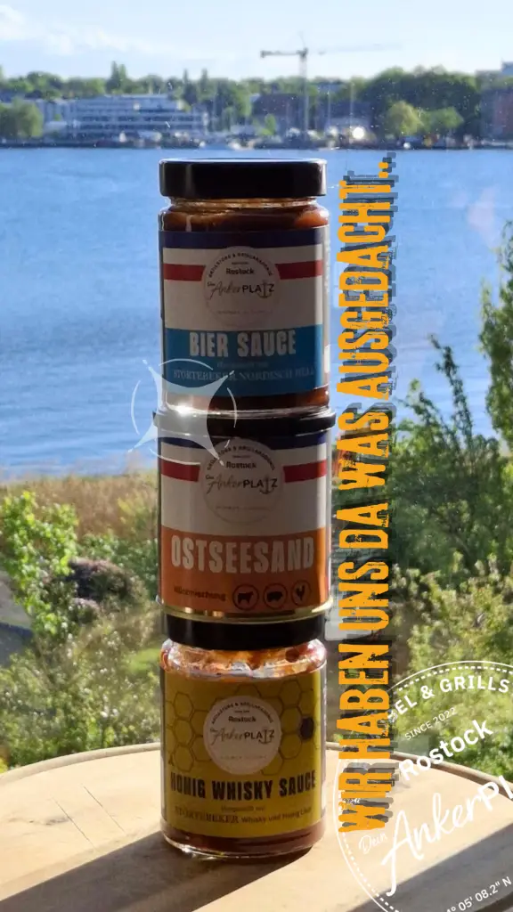 Honig Whisky Sauce und zwei weitere Gewürzgläser stehen auf einem Tisch am Fenster mit Blick auf einen sonnigen See. Gartenmöbel und Grills kaufen in Rostock, Mecklenburg-Vorpommern.