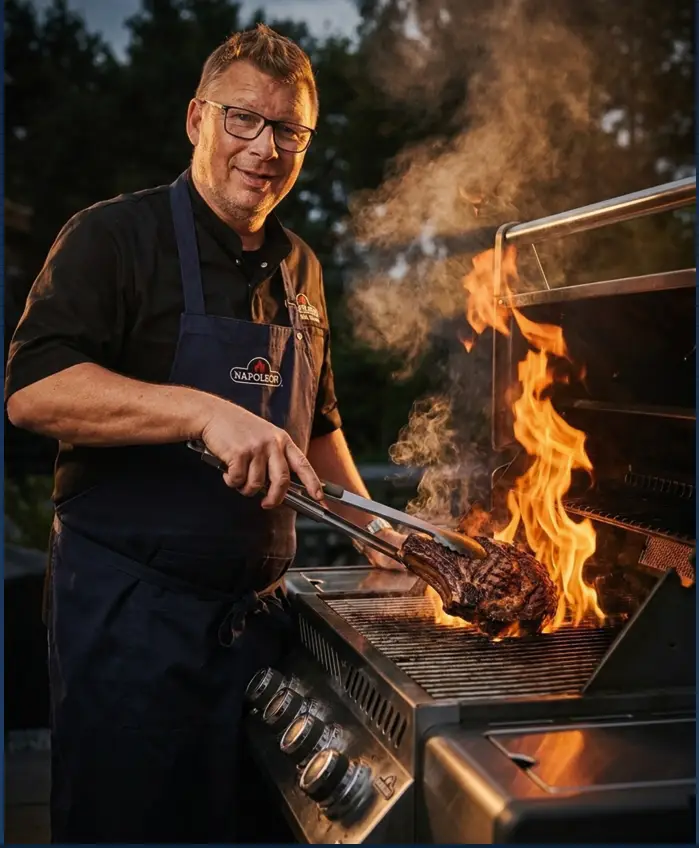 Andreas Rummel grillt ein Steak beim Grillkurs Premium Spezial – mit Schutzbrille, Schürze und einem Lächeln am Grill. Gartenmöbel und Grills kaufen in Rostock, Mecklenburg-Vorpommern.